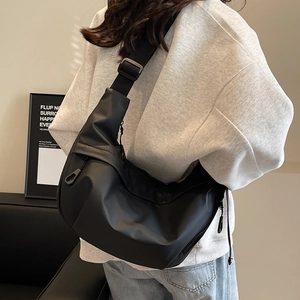 Minimalist black nylon half-moon crossbody bag with adjustable wide shoulder strap on model