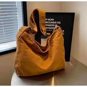 Macro shot of ginger yellow canvas tote bag featuring adjustable strap and zipper closure