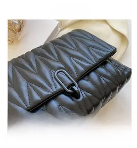 Macro shot of V-quilted black leather texture and matte metal buckle on crossbody bag
