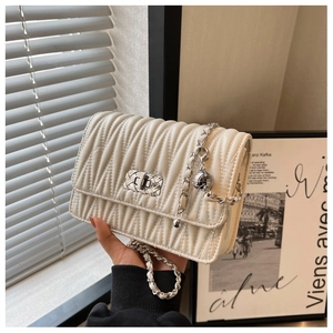 Detail of cream quilted crossbody bag featuring silver woven lock and vertical pleats