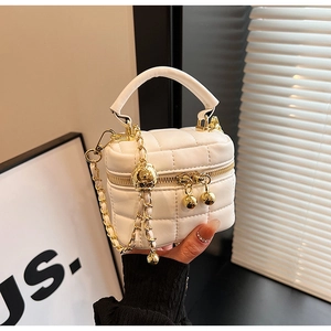 Detail of white quilted vanity bag with gold chain strap and spherical metal charm