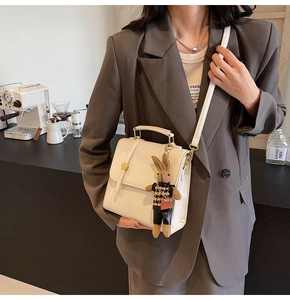 Chic cream leather backpack shown as a crossbody bag with a cute rabbit charm detail