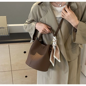 Detail of a brown bucket bag with a fashion scarf handle and long shoulder strap