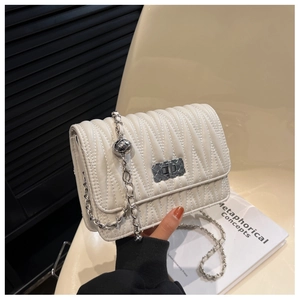 Detail of cream-colored pleated leather bag with silver chain and sphere metal charm