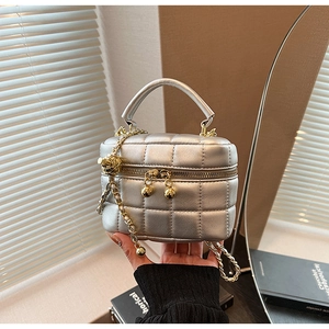 Close-up of silver quilted leather handbag with gold chain strap and ball adjuster