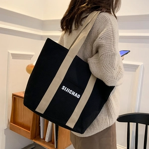 Large black canvas tote bag with beige straps and white letter print for daily commute
