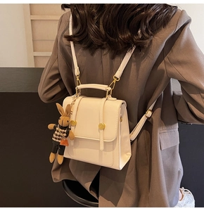Detail of cream leather backpack featuring a vintage gold clasp and cute rabbit charm
