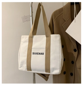 Detail of white canvas tote bag with khaki straps and front pocket for daily commute