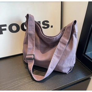 Detail of purple canvas hobo bag with adjustable wide strap on a wooden surface