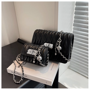 Detail of black quilted leather shoulder bags with silver chain straps and metal charms