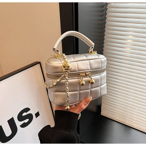 Close-up of silver quilted box bag with golden chain strap and ball zipper detail
