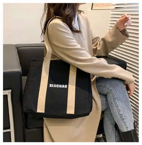 Close-up of black canvas tote bag with contrast straps and text print for daily use