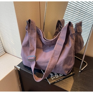 Detail view of purple canvas tote bag with adjustable wide strap on a wooden surface