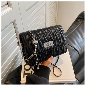 Detail of black matelassé quilted shoulder bag with silver turn-lock and metal chain strap
