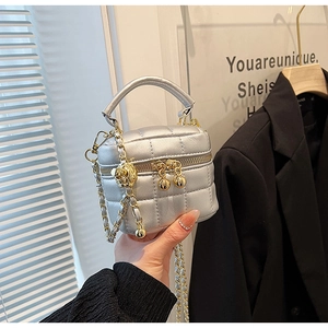 Detail of silver quilted bucket bag featuring a golden adjustable ball on chain strap