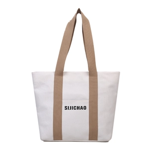 Minimalist white canvas tote bag with brown straps and front pocket for daily commute