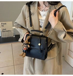 Detail of vintage black leather backpack with gold buckle and cute rabbit doll charm