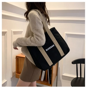 Detail of black canvas tote bag with contrast cream strap and SIJICHAO print