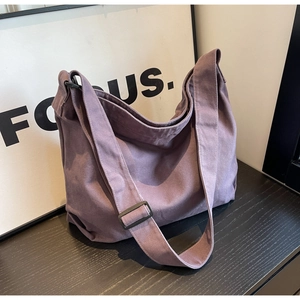 Detail of purple canvas tote bag featuring wide adjustable strap and black buckle