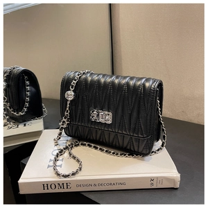 Detail of wave quilted faux leather on a black chain shoulder bag with silver hardware