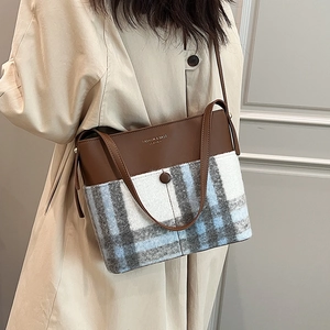 Women's large bucket bag in brown leather and plaid fabric shown from a side profile
