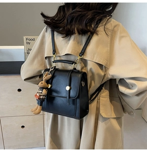 Detail of minimalist black leather mini backpack with gold hardware and rabbit charm