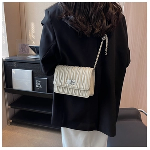 Detail of off-white pleated crossbody bag with silver chain strap and metal swivel lock