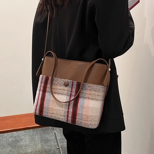 Brown leather and plaid wool bucket bag worn by a model in a black blazer suit