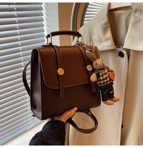 Detail of vintage brown PU leather backpack with gold buckles and plush rabbit charm