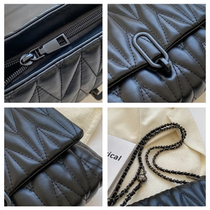 Detail view of V-shaped quilted leather, metal zipper, oval lock and adjustable chain strap