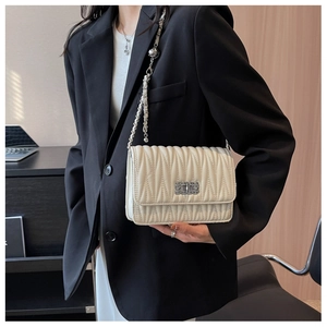 Close-up of quilted beige crossbody bag with silver chain strap and metal buckle