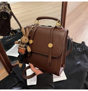 Detail of vintage brown PU leather backpack with gold buckle and a cute rabbit charm