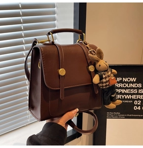 Detail of vintage brown PU leather handbag featuring gold buckles and a cute rabbit charm
