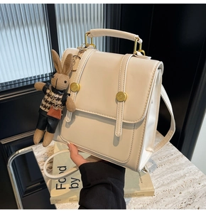 Detail of cream PU leather square backpack with golden rivets and rabbit plush charm