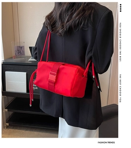 Detail of red nylon square bag with drawcord strap and buckle, modeled on a black blazer