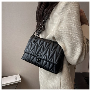 Quilted black chain bag with wave stitching and metal U-lock shown on a shoulder
