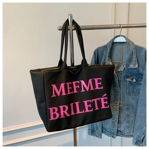 Détail du grand sac cabas noir en toile montrant les lettres roses et la fermeture éclair