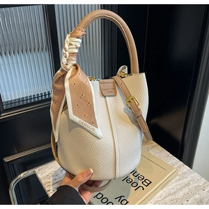 Detailed close-up of white lychee leather bucket bag with bear print silk scarf handle