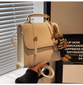 Detail of off-white PU leather backpack with a decorative bunny charm and metal buckle