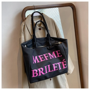 Détail d'un grand cabas en toile noire avec lettrage rose MEFME BRILETÉ et fermeture éclair