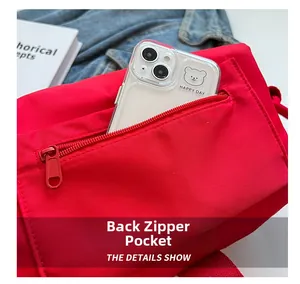 Detail shot of the rear zipper pocket on a red nylon crossbody bag with mobile phone inside