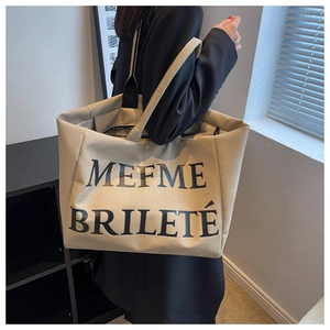 Vue latérale détaillée d'un grand sac cabas en toile beige avec lettrage artistique noir