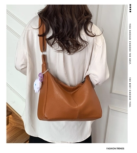 Close-up of caramel tote bag with litchi texture leather and a plush white charm