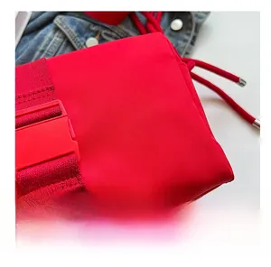 Close-up of red nylon bag details with plastic buckle and woven strap on denim background