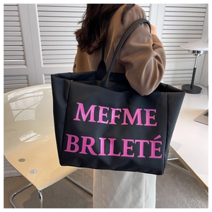 Détail du grand cabas noir avec texte MEFME BRILETÉ rose sur une bandoulière chic