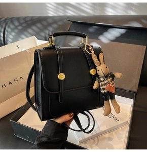 Unboxing detail of a black vintage backpack with golden buckle and rabbit charm