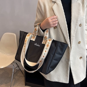 Grande borsa tote in nylon nero con tracolla a motivi mostrata su una modella