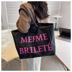 Gros plan sur un grand sac cabas en toile noire avec imprimé MEFME BRILETÉ rose et longue bandoulière
