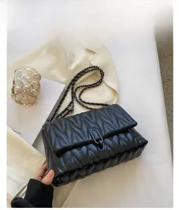 Close-up of black quilted leather bag featuring V-shaped stitching and U-shaped magnetic buckle