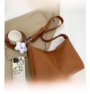 Close-up of brown PU tote bag with decorative stitching on professional blazer background